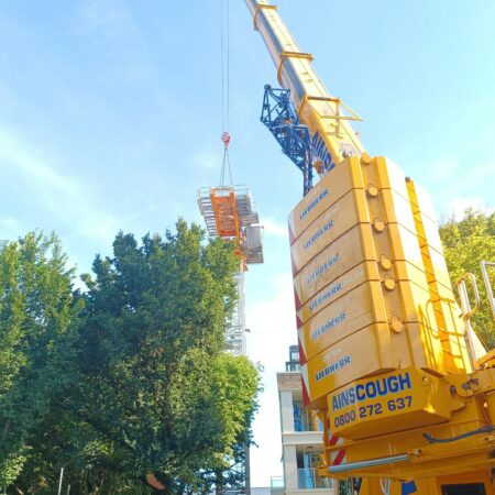 Bright yellow tower crane being dismantled on site in Hove on a sunny day